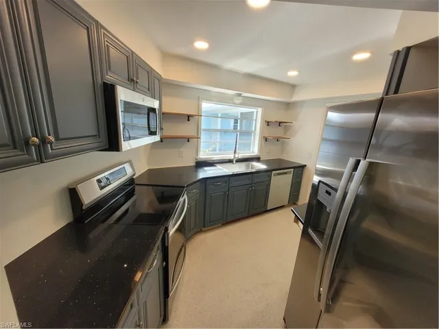 Kitchen with stainless steel appliances, open shelves, recessed lighting, gray cabinets, and dark stone counters