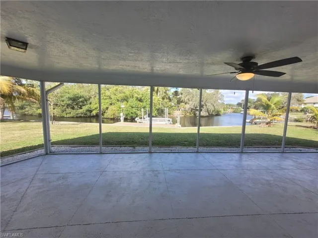 Unfurnished sunroom featuring ceiling fan and a water view