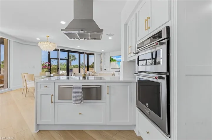 Kitchen featuring white cabinets, light hardwood / wood-style flooring, island exhaust hood, and double oven