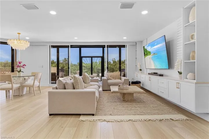 Living room with expansive windows, light hardwood / wood-style flooring, a wealth of natural light, and an inviting chandelier