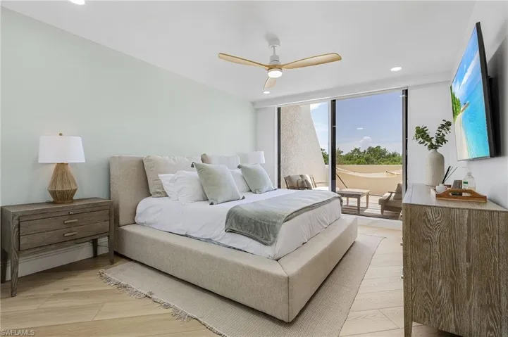Bedroom featuring expansive windows, light wood-type flooring, and ceiling fan