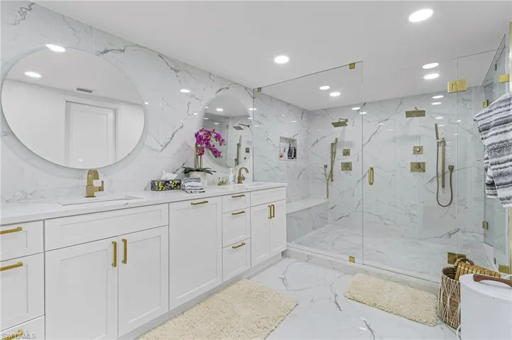 Bathroom with tile patterned floors, double sink vanity, an enclosed shower, and tile walls