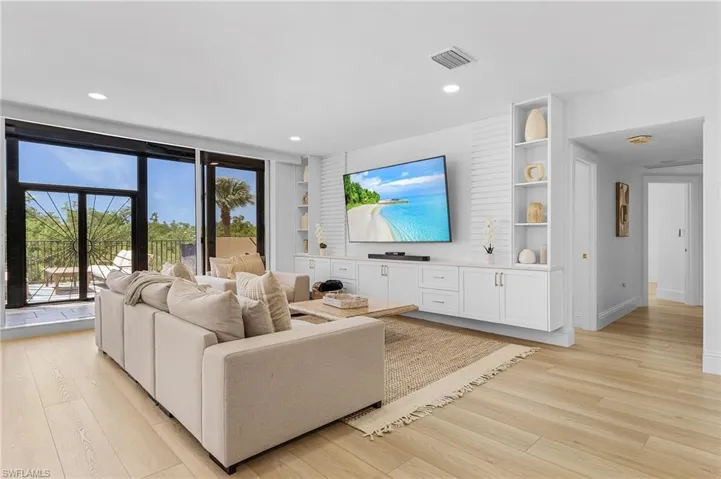 Living room with built in shelves and light hardwood / wood-style floors