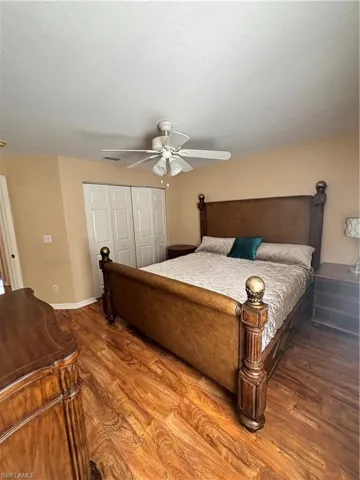 Bedroom with dark wood finished floors, a closet, and a ceiling fan