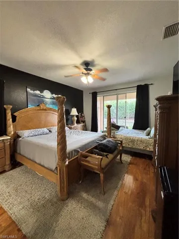 Bedroom featuring a textured ceiling, dark wood-style floors, a ceiling fan, and access to exterior