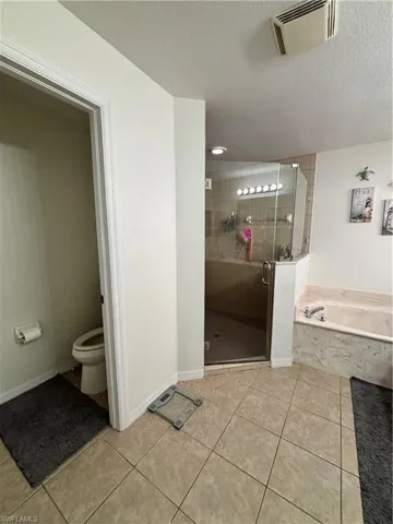 Full bathroom with a stall shower, a bath, light tile patterned flooring, and a textured ceiling