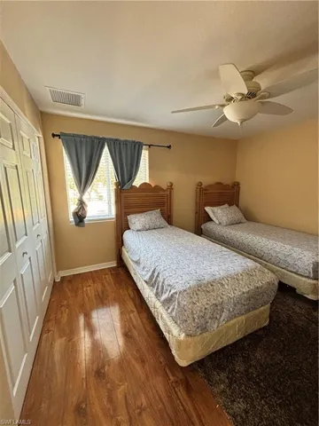 Bedroom featuring dark wood-style flooring, a closet, and a ceiling fan