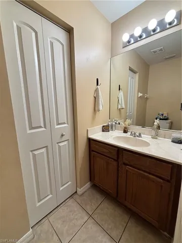 Bathroom featuring vanity, light tile patterned floors, and a closet