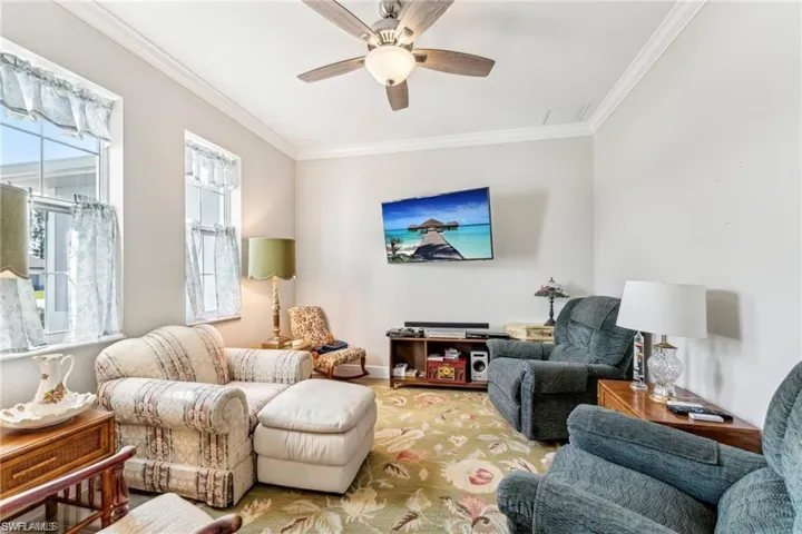Living area with baseboards, ceiling fan, and crown molding
