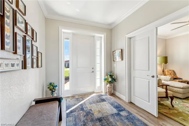 Entrance foyer featuring baseboards, ornamental molding, light wood-style floors, and a ceiling fan