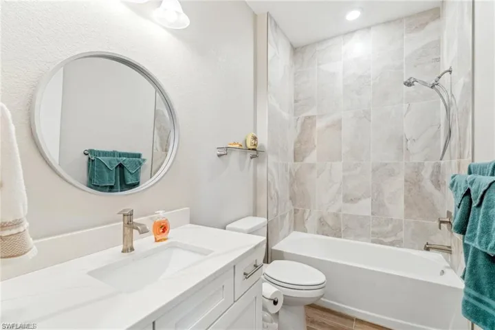 Bathroom featuring toilet, vanity, bathtub / shower combination, and wood finished floors