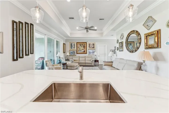 Kitchen featuring visible vents, light stone countertops, a ceiling fan, a sink, and open floor plan