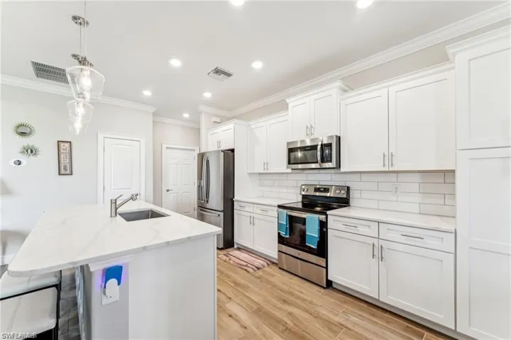 Kitchen with crown molding, decorative backsplash, a sink, visible vents, and appliances with stainless steel finishes