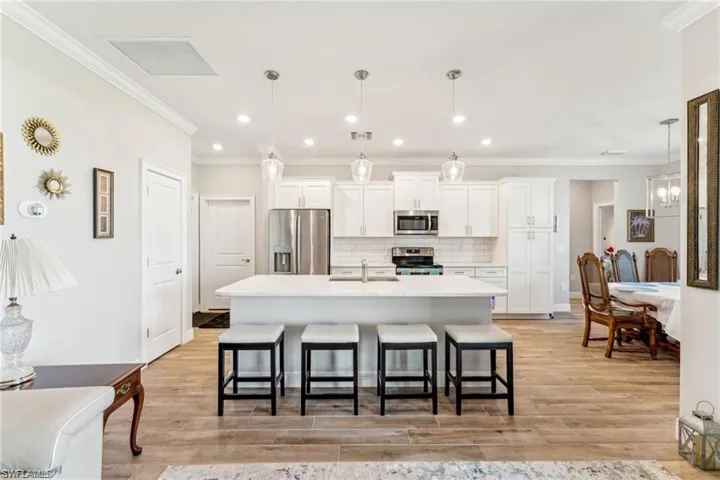 Kitchen with white cabinetry, a sink, a kitchen breakfast bar, and appliances with stainless steel finishes