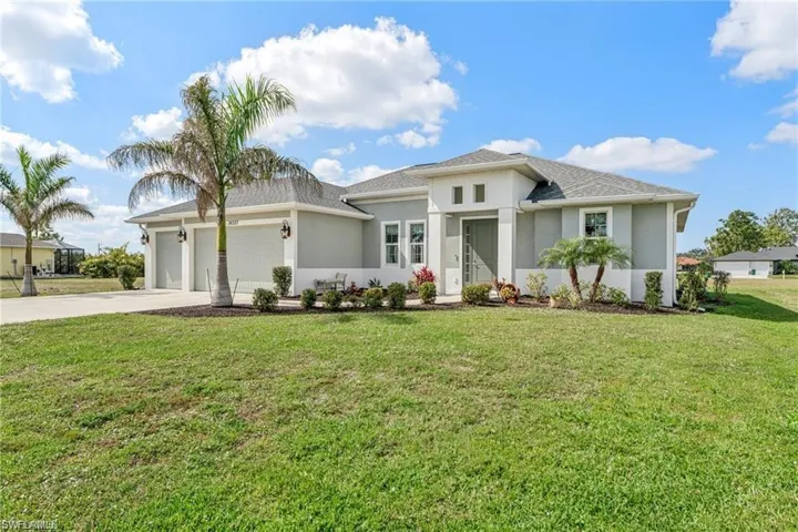 View of front facade with a front yard, concrete driveway, stucco siding, and an attached garage