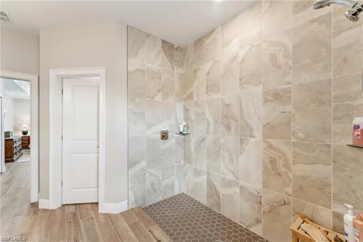 Full bath with wood tiled floor, visible vents, and tiled shower