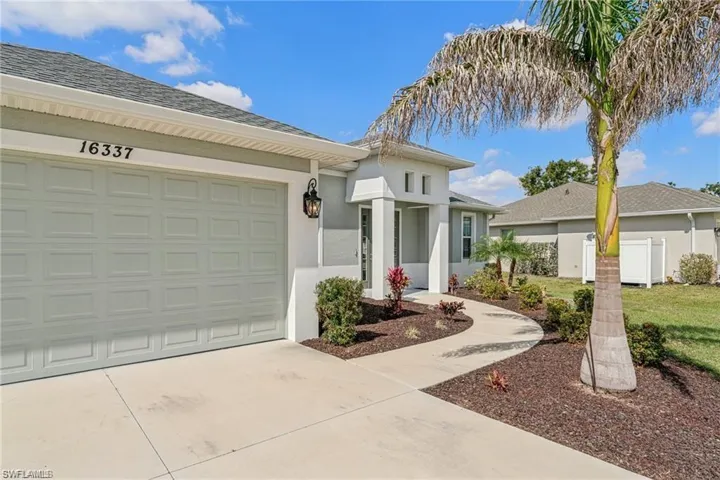 View of front of house featuring driveway, stucco siding, an attached garage, and fence