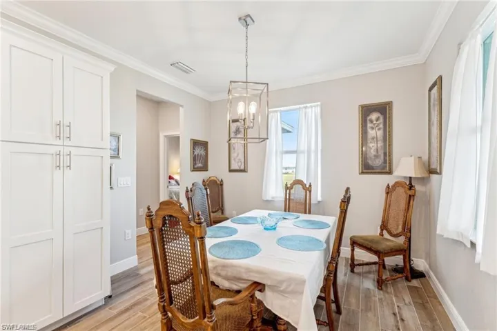 Dining space featuring baseboards, visible vents, a notable chandelier, and light wood-style flooring