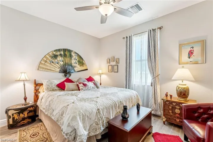 Bedroom with a ceiling fan, wood finished floors, and visible vents