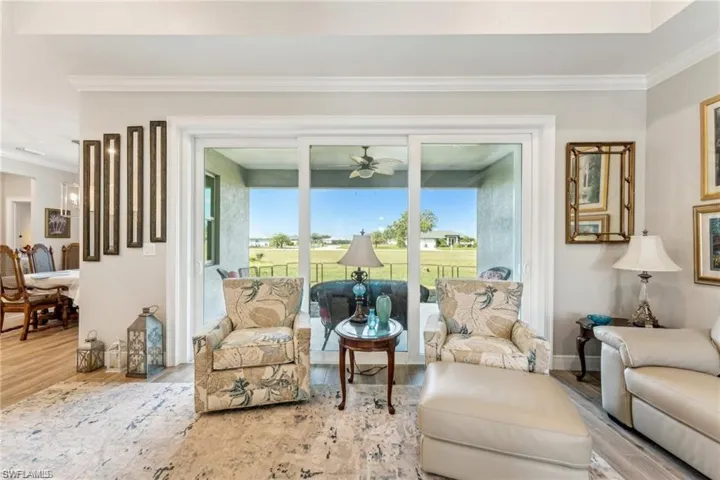 Living room with baseboards, wood finished floors, ornamental molding, and a ceiling fan