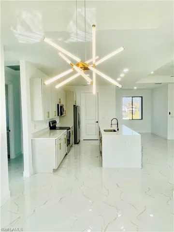 Kitchen with light marble finish flooring, white cabinetry, stainless steel appliances, light stone counters, and recessed lighting