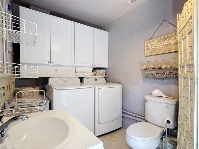 Bathroom featuring tile patterned floors, sink, washer and clothes dryer, and toilet