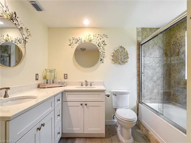 Full bathroom with wood-type flooring, shower / bath combination with glass door, vanity, and toilet