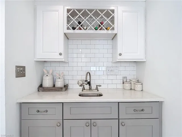 Coffee/Wine Bar featuring gray cabinetry, decorative backsplash, sink, and light quartz countertops