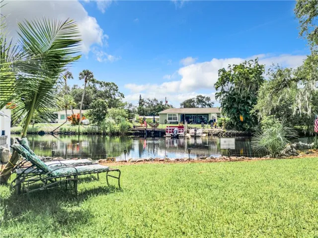 View of dock featuring a oversized lawn and a river view