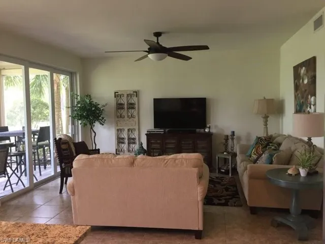 Tiled living room featuring a ceiling fan