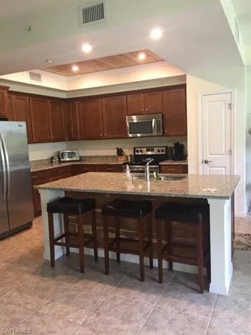 Kitchen featuring a breakfast bar area, recessed lighting, a tray ceiling, and appliances with stainless steel finishes