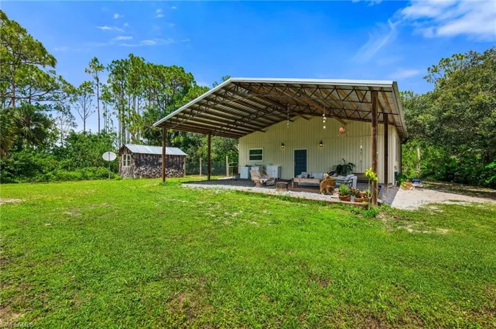 Back of house featuring a lawn, an outdoor structure, and an outdoor hangout area
