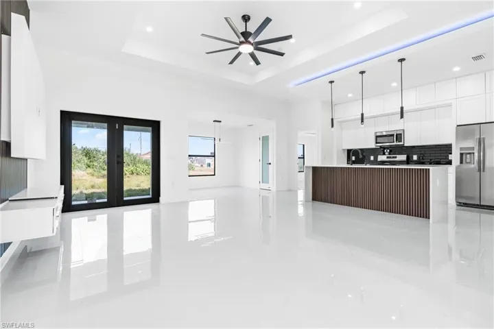 Kitchen with appliances with stainless steel finishes, decorative light fixtures, a kitchen island, and a raised ceiling