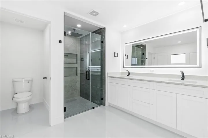 Bathroom featuring vanity, toilet, and an enclosed shower