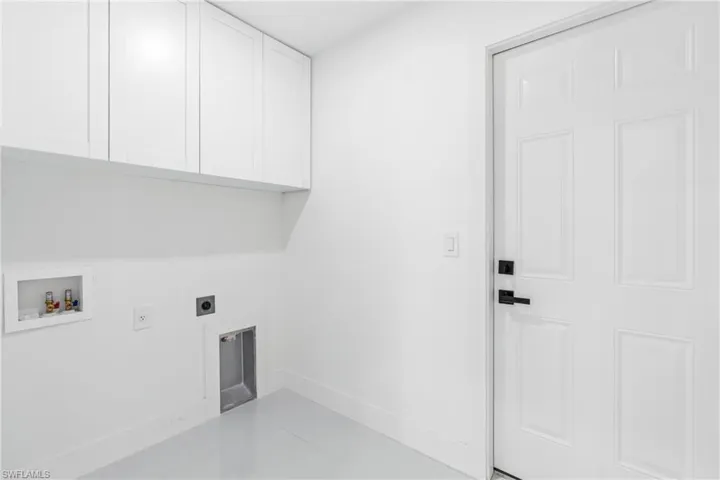 Clothes washing area featuring hookup for an electric dryer, hookup for a washing machine, light tile patterned floors, and cabinets