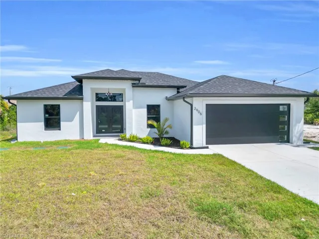 Prairie-style home with an attached garage, a front lawn, driveway, and stucco siding