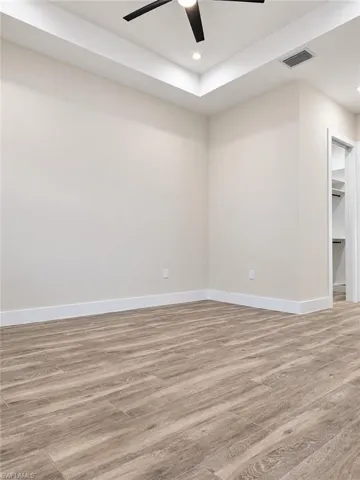 Recessed lighting, wood-finish flooring, ceiling fan, white baseboards, and a closet with built-in shelving