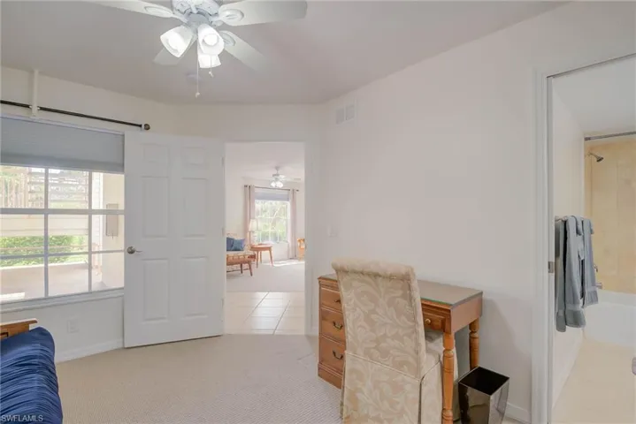 Office space with ceiling fan, light tile patterned floors, and light colored carpet