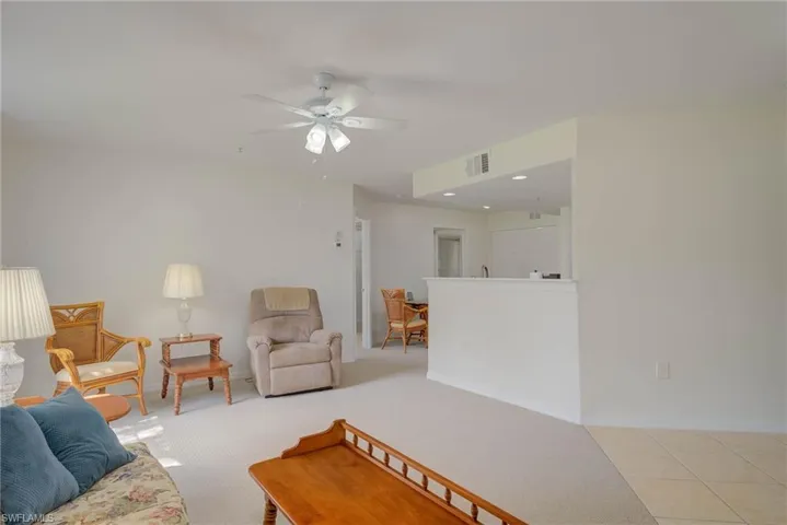 Living room with ceiling fan and light carpet