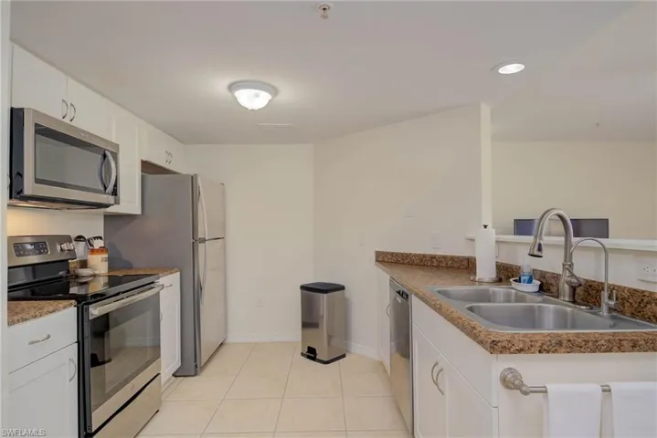 Kitchen featuring stainless steel appliances, white cabinetry, a peninsula, light tile patterned floors, and recessed lighting