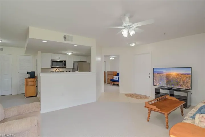 Living room with ceiling fan, light colored carpet, and recessed lighting