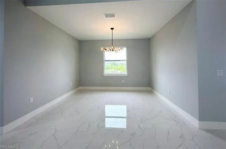 Tiled empty room with an inviting chandelier