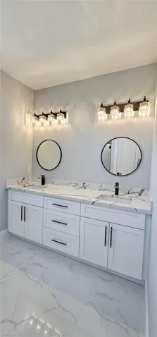 Bathroom featuring dual bowl vanity and tile flooring