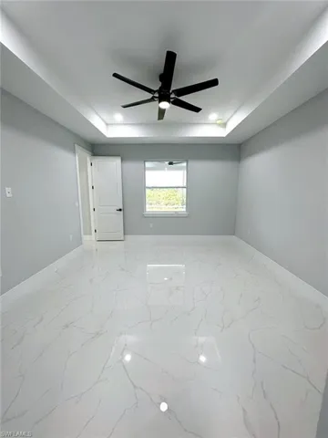 Empty room with ceiling fan and a raised ceiling