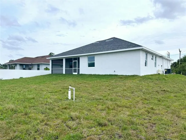 Back of property featuring central AC and a lawn