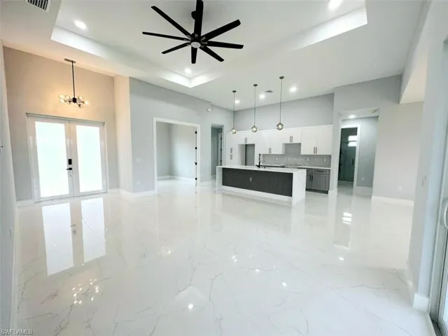 Kitchen with french doors, hanging light fixtures, ceiling fan with notable chandelier, a tray ceiling, and backsplash