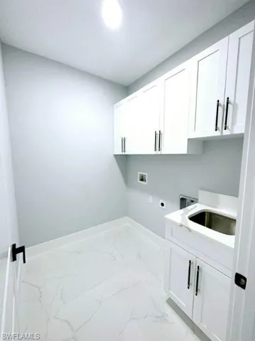 Laundry area featuring cabinets, washer hookup, electric dryer hookup, sink, and light tile flooring