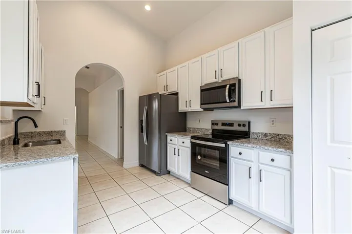 Kitchen featuring ALL NEW stainless steel appliances, sink, white cabinetry light stone counters