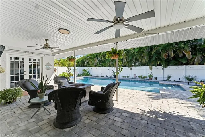 View of pool featuring ceiling fan, a patio, a fire pit, and french doors