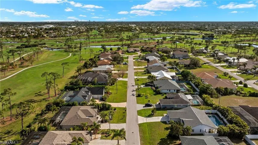 Aerial perspective of suburban area featuring a nearby body of water and a golf club